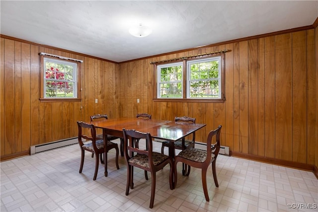 dining room with baseboard heating, wood walls, and a wealth of natural light