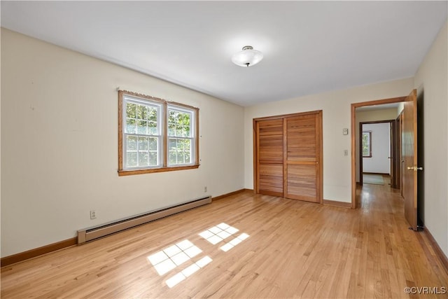 unfurnished bedroom featuring light wood-type flooring, baseboards, baseboard heating, and a closet