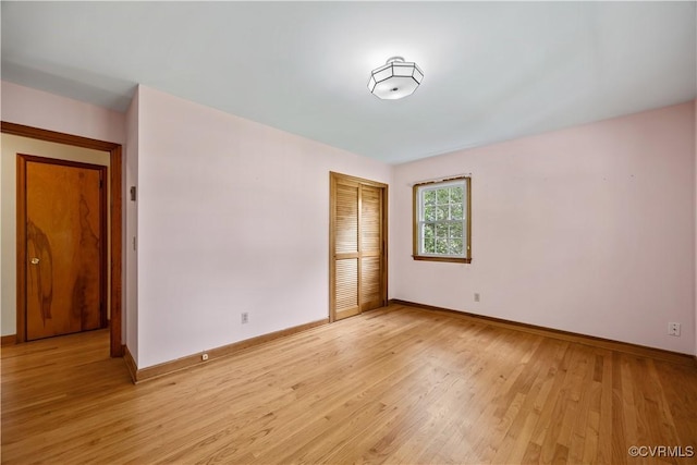 spare room featuring baseboards and light wood finished floors