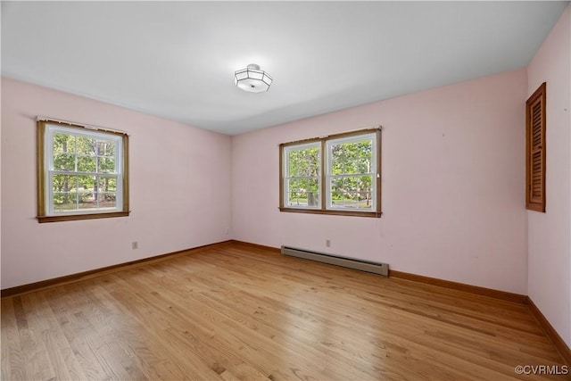 spare room with light wood-style floors, baseboards, and a baseboard heating unit
