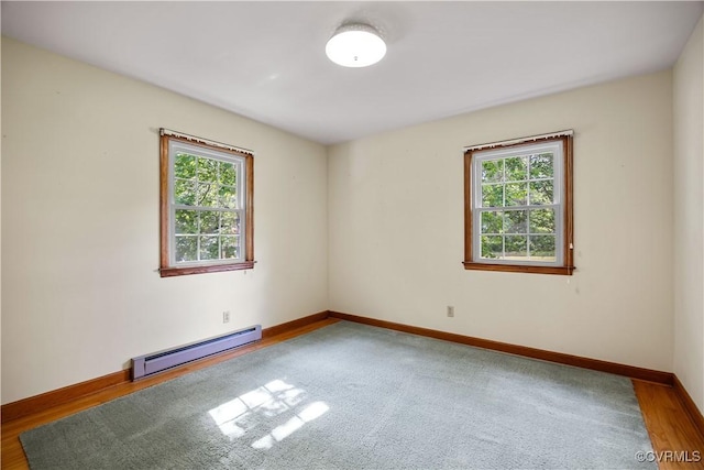 empty room with baseboards, a baseboard heating unit, and a wealth of natural light