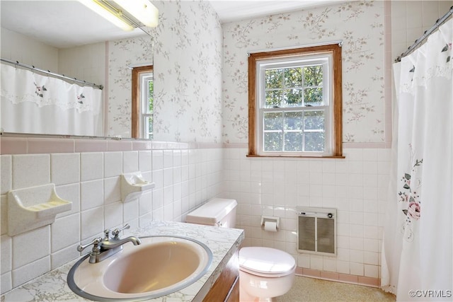 full bath featuring heating unit, tile walls, wainscoting, and wallpapered walls