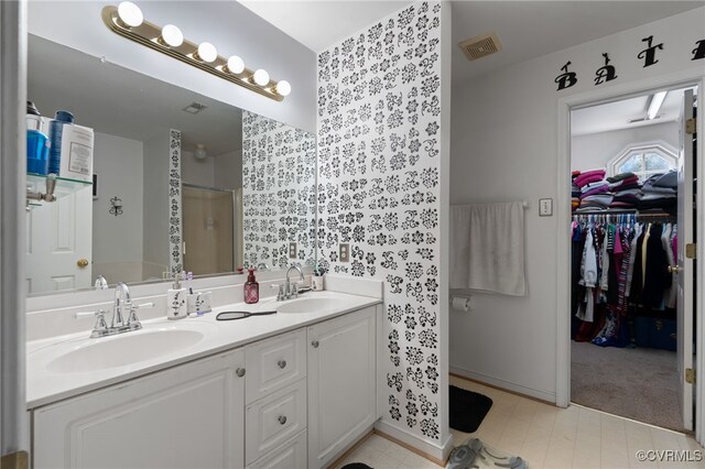 bathroom with visible vents, a sink, double vanity, and a shower stall