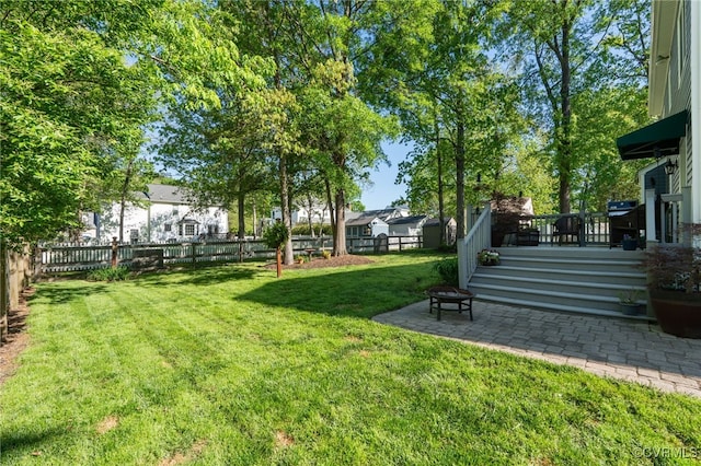 view of yard with a fenced backyard, a deck, a fire pit, and a patio area