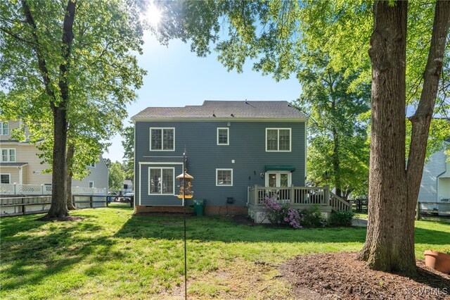 rear view of house featuring a yard, a deck, and fence