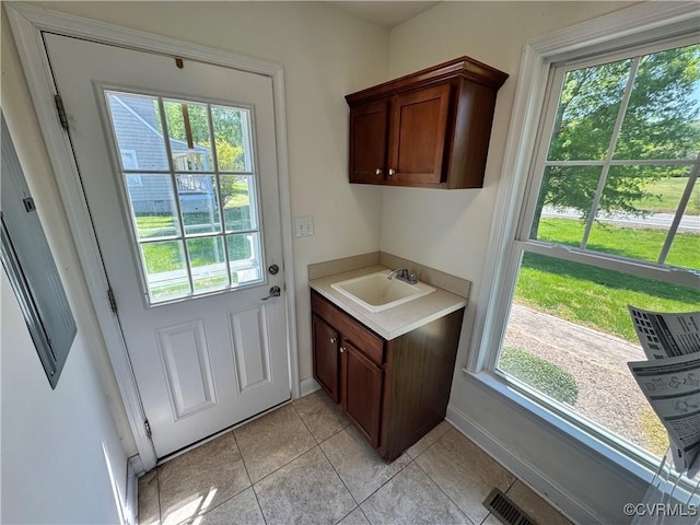entryway with baseboards, a sink, light tile patterned flooring, and visible vents