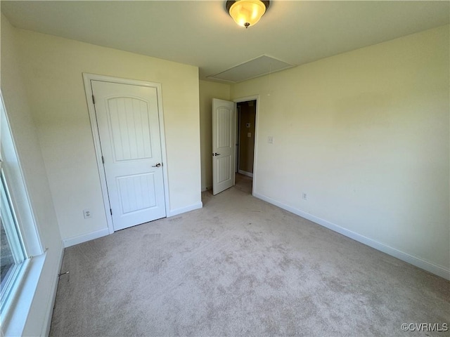 unfurnished bedroom featuring baseboards, attic access, and carpet flooring