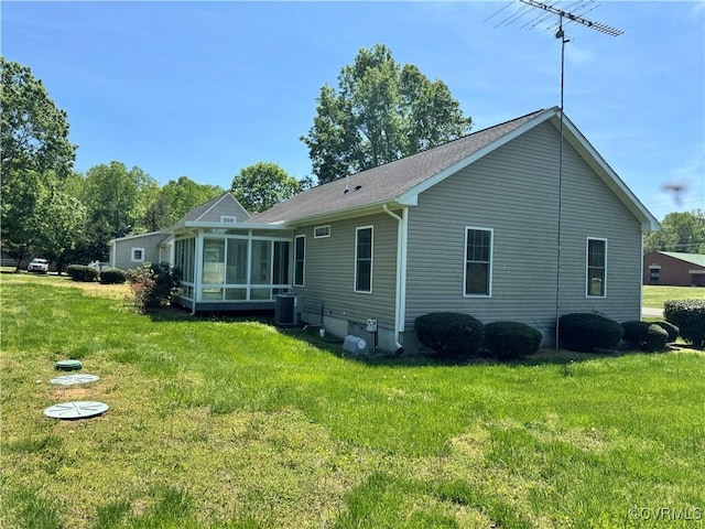 back of house featuring a sunroom, a shingled roof, a lawn, and central AC