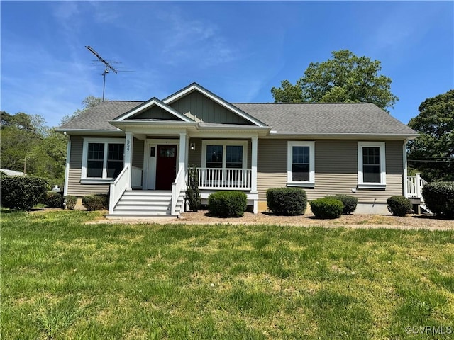 view of front of property with covered porch, roof with shingles, and a front lawn