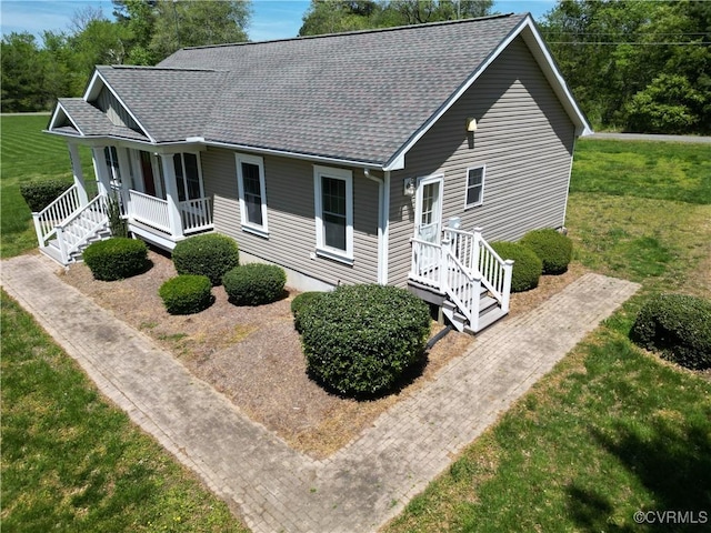view of front of property featuring a shingled roof, a porch, and a front yard