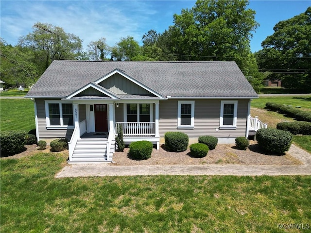 view of front of home with covered porch, a front yard, and roof with shingles