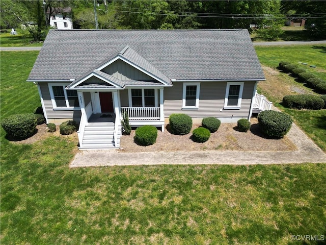 view of front of property featuring covered porch, a shingled roof, stairs, and a front yard