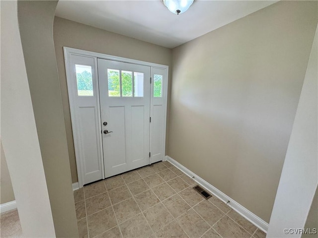 foyer entrance with baseboards, arched walkways, and visible vents