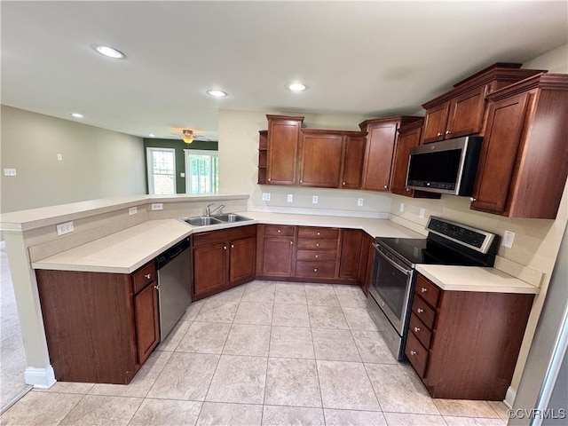 kitchen featuring a sink, appliances with stainless steel finishes, a peninsula, and light countertops