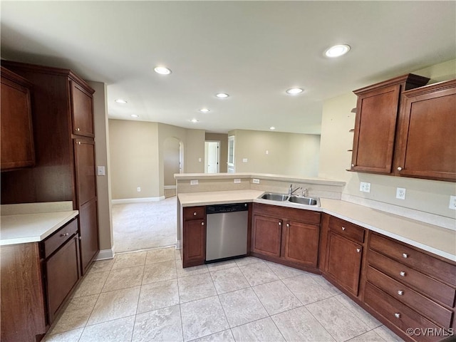 kitchen featuring stainless steel dishwasher, a peninsula, light countertops, arched walkways, and a sink