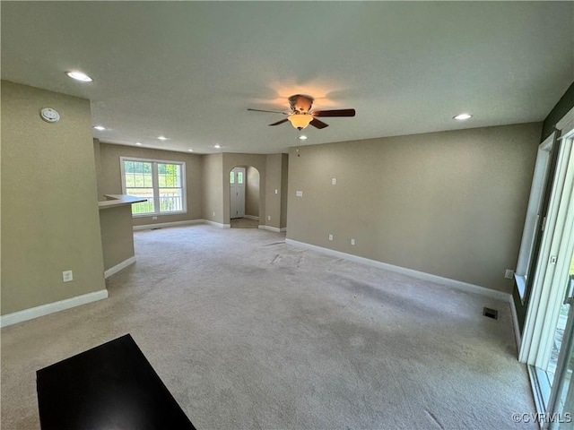 unfurnished room with recessed lighting, arched walkways, a ceiling fan, and light colored carpet