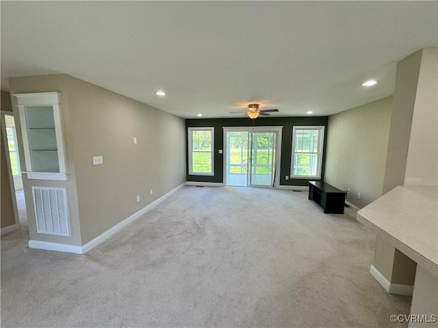 unfurnished living room with baseboards, light colored carpet, recessed lighting, and visible vents