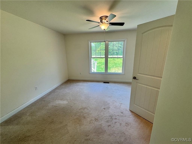 carpeted spare room featuring baseboards and a ceiling fan