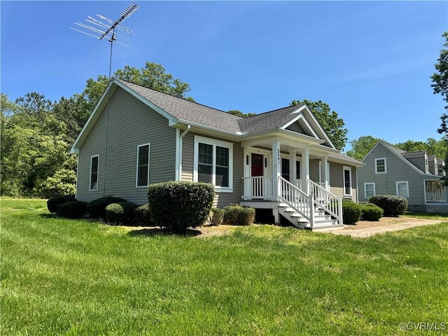 view of front facade with roof with shingles, covered porch, and a front yard