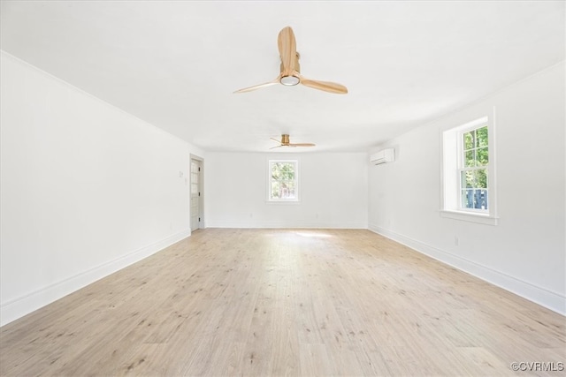 unfurnished room with a ceiling fan, an AC wall unit, light wood-style flooring, and a wealth of natural light