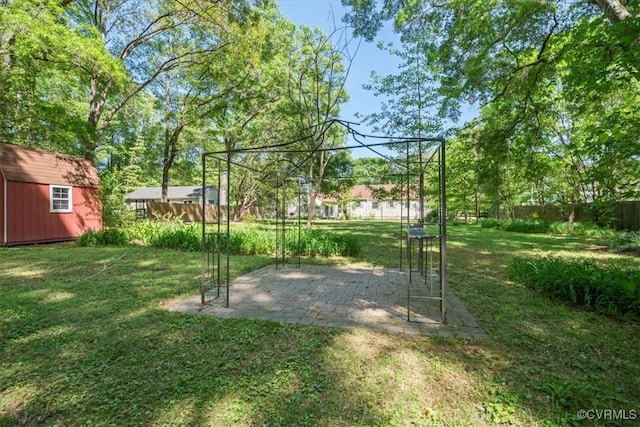 view of yard featuring a storage shed, a patio, fence, and an outdoor structure