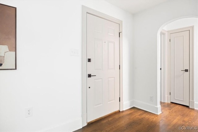 interior space featuring baseboards, arched walkways, and wood finished floors