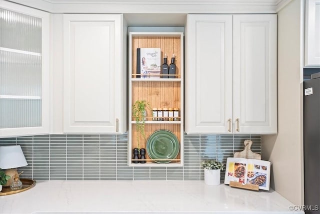 room details featuring light stone counters, decorative backsplash, and white cabinetry