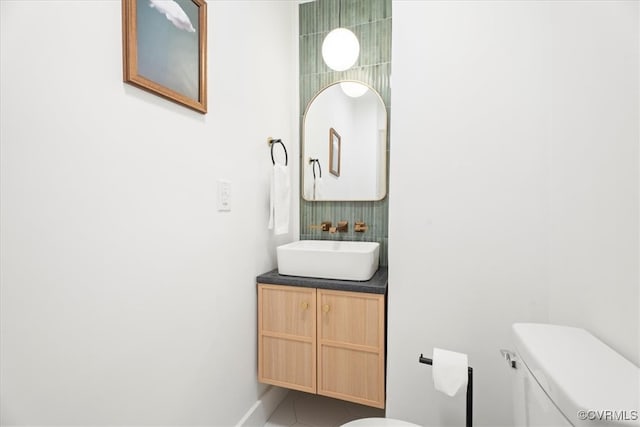 half bath featuring toilet, tile patterned floors, baseboards, and vanity
