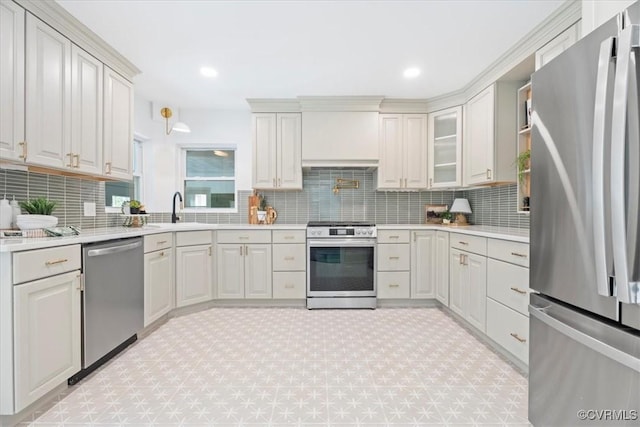 kitchen with decorative backsplash, appliances with stainless steel finishes, a sink, light countertops, and light carpet