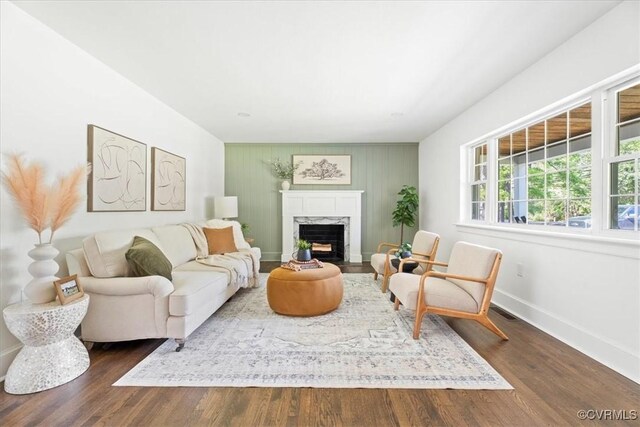 living room featuring baseboards, a high end fireplace, and dark wood-type flooring