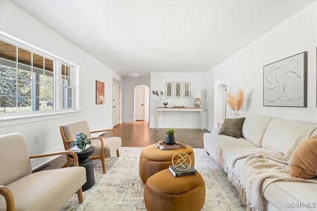 living area featuring baseboards, arched walkways, and wood finished floors