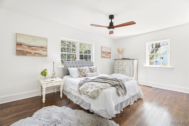 bedroom with baseboards, wood finished floors, and multiple windows