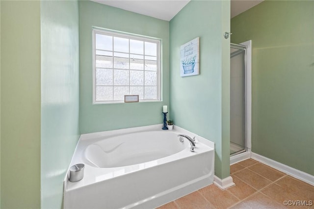bathroom with a garden tub, tile patterned flooring, baseboards, and a stall shower