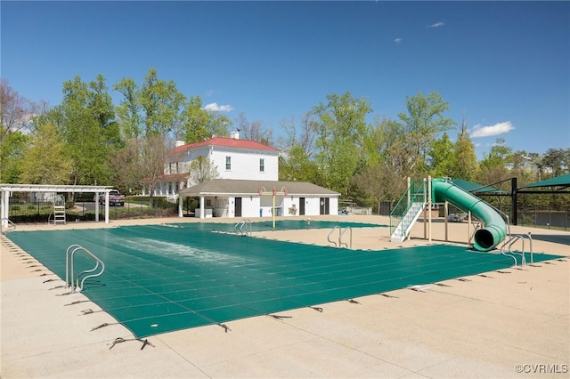 community pool featuring fence, a water slide, and playground community