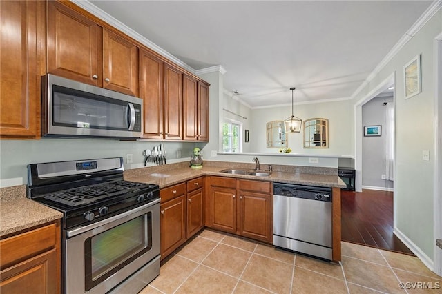 kitchen featuring brown cabinets, a sink, a peninsula, ornamental molding, and stainless steel appliances