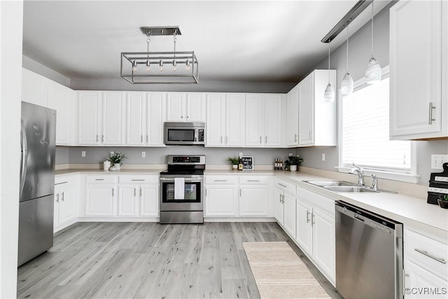 8134 Falling Leaf Ct, Mechanicsville, VA 23111 - kitchen with stainless steel appliances, light wood-style floors, white cabinetry, light countertops, and decorative light fixtures