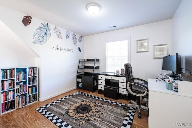 office space with baseboards, visible vents, and wood finished floors