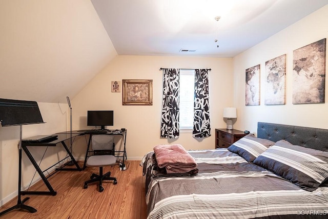 bedroom featuring baseboards, vaulted ceiling, wood finished floors, and visible vents