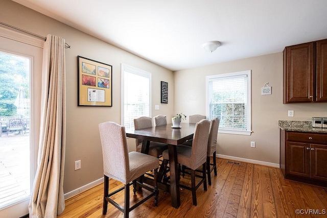 dining space with baseboards, light wood-style flooring, and visible vents
