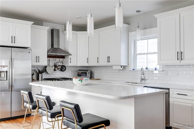 1207 N 21st St, Richmond, VA 23223 - kitchen with a kitchen island, wall chimney range hood, a kitchen bar, a sink, and stainless steel appliances