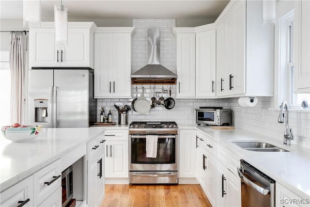 1207 N 21st St, Richmond, VA 23223 - kitchen with wall chimney range hood, appliances with stainless steel finishes, a sink, light countertops, and white cabinetry