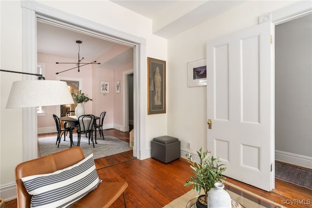 sitting room with an inviting chandelier, baseboards, and hardwood / wood-style floors