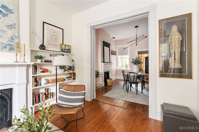 sitting room with baseboards, a fireplace with flush hearth, and dark wood finished floors