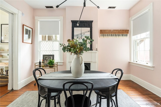 dining room featuring visible vents, light wood-style flooring, baseboards, and a fireplace