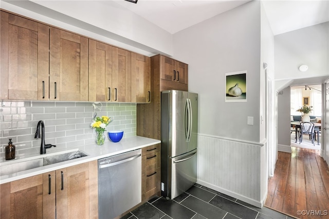 kitchen with brown cabinetry, tasteful backsplash, a sink, light countertops, and stainless steel appliances