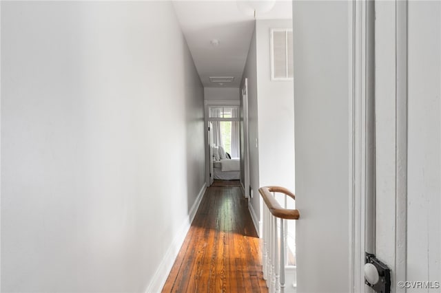 hallway with visible vents, baseboards, and hardwood / wood-style flooring