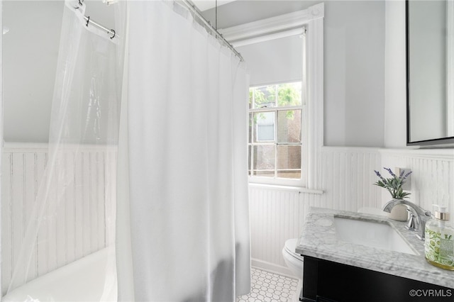 bathroom with vanity, toilet, curtained shower, and a wainscoted wall