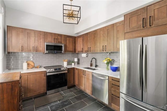 kitchen featuring a sink, brown cabinetry, stainless steel appliances, backsplash, and dark tile patterned floors