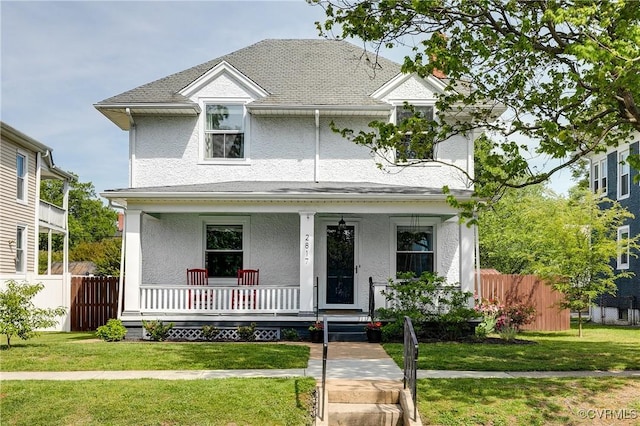 view of front facade featuring a front lawn, stucco siding, covered porch, and fence