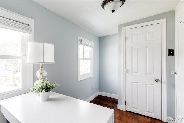 unfurnished office featuring baseboards, dark wood-style flooring, and a healthy amount of sunlight